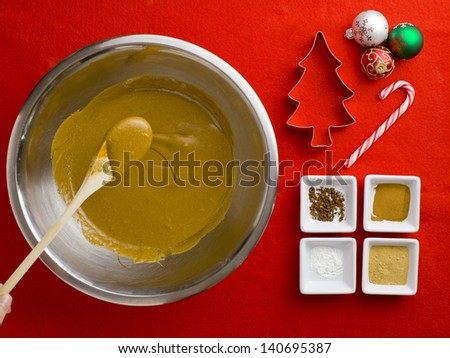Close-up top view of a person holding spatula in chocolate syrup with cake ingredient over plain red background.