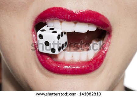 Close up image of woman with red lips biting dice