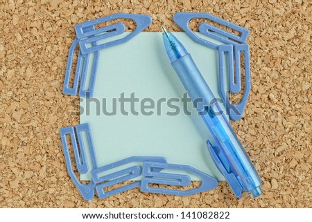 Image of blue adhesive paper with paper clip and ball pen