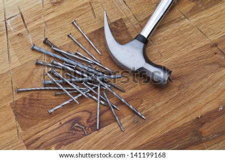 A pile of nails and a hammer on a table