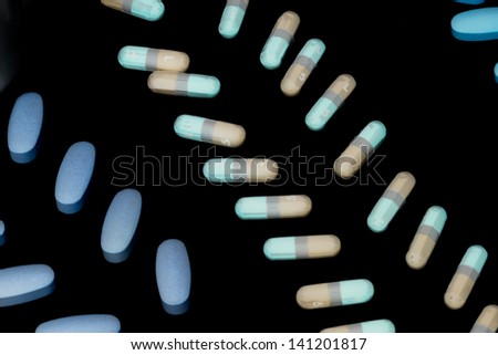 Detailed shot of capsules arranged in a row against plain dark background.