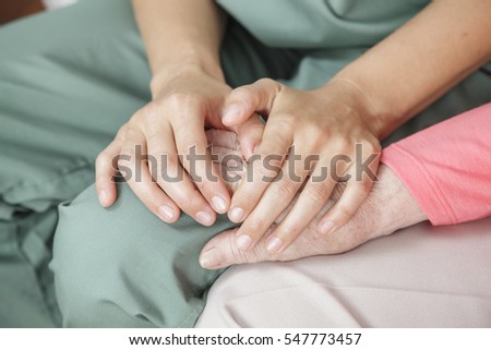 Nurse holding the hand of an elderly woman - closeup detail image.