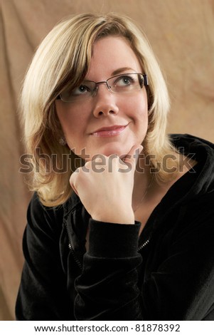 Female portrait, soft sensual studio shot in warm light against a light brown fabric background.