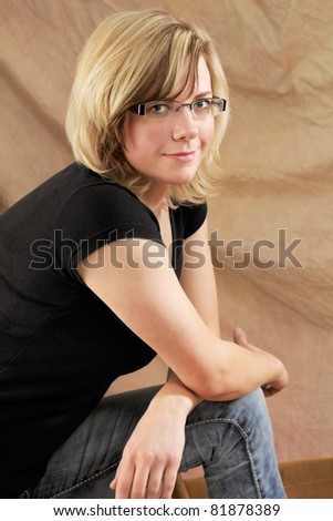 Young woman portrait, soft studio shot in warm light against a light brown fabric background.