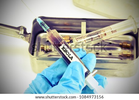Doctor with latex glove holds a syringe in his hand with the virulent blood infected with the ebola virus with vintage effect