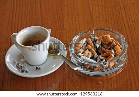 ashtray chock full of cigarette butts and a cup of espresso