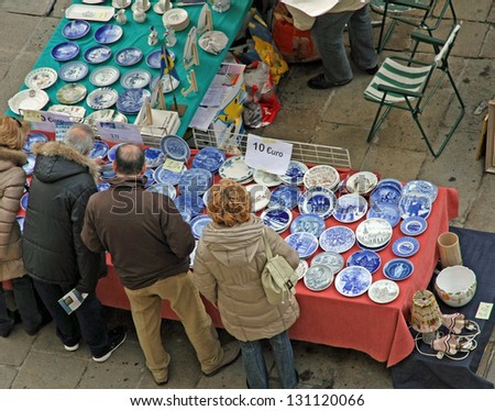 adults who watch the stalls where there are decorated plates for sale at the market