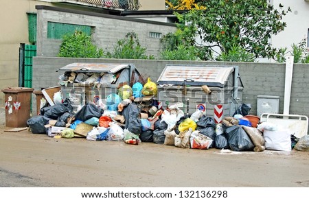 bags of rubbish and waste bins in the middle of the road full of mud