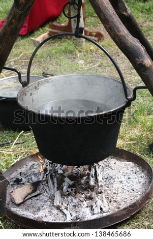 ancient medieval pot with water on the fire and tripods to support