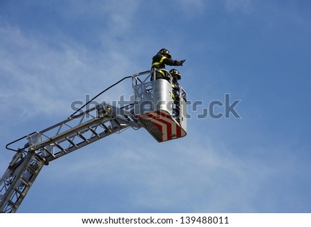 firefighters in the basket of the scale of the fire truck when switching off a fire