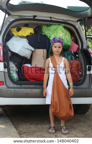 beautiful little girl with a brown bag and baggage of the car