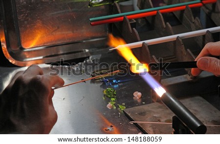 Glazier with gas torch lit while blending and shaping a piece of glass 5