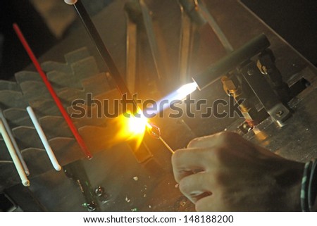 Glazier with gas torch lit while blending and shaping a piece of glass 1