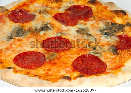 pizza with pepperoni and mushrooms and mozzarella baked in wood-fired oven