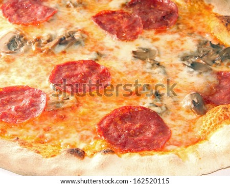 tasty pizza with pepperoni and mushrooms cooked in wood-fired oven
