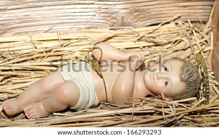 Baby Jesus is laid in the cradle in a manger with folded hands praying