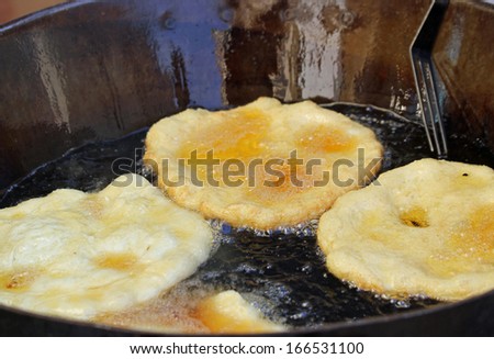 tasty Fried Apple fritters in the cauldron of boiling oil on sale at the market