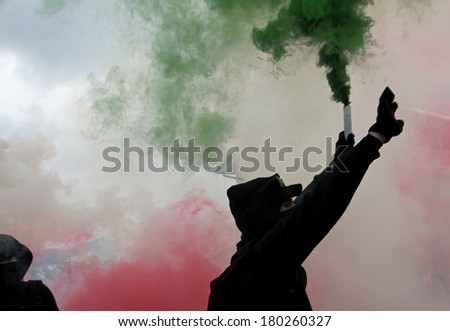 violent protest with protesters wearing black gloves with green smoke