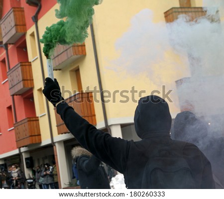 protest with protesters dressed in black robes with green smoke and red and white