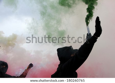 violent protest with protesters dressed in black robes with green and red smoke