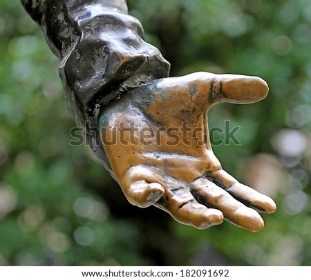 bronze hand stretches to offer something to people