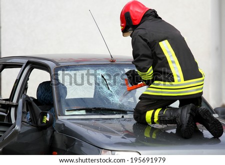 Fireman with protective overalls and work gloves while breaking a car windshield