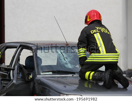 Italian fireman while breaks the glass windshield broken car to rescue the injured persons