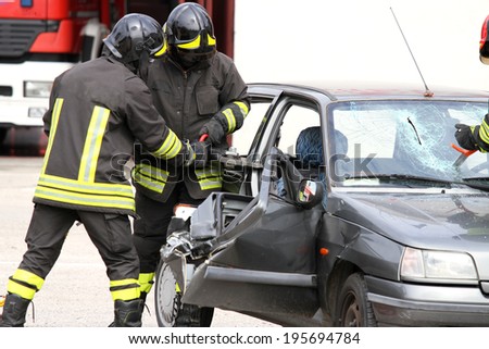 brave firefighters with pneumatic shears open the car doors