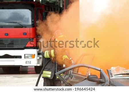 Firefighter  uses a hydrant toward a car with smoke