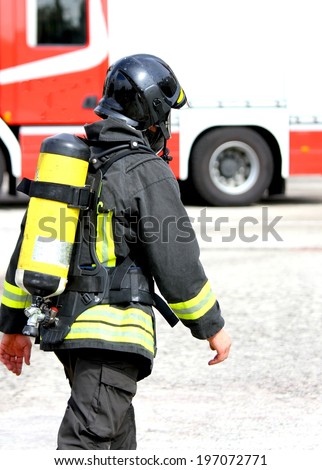 Italian firefighter with the oxygen cylinder and the helmet walks towards the fire