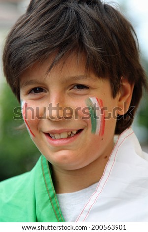 Nice smiling boy with flag painted on the cheeks and wrapped in the Tricolor flag