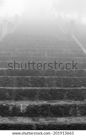 long marble staircase that leads upwards on a cold day with dense fog
