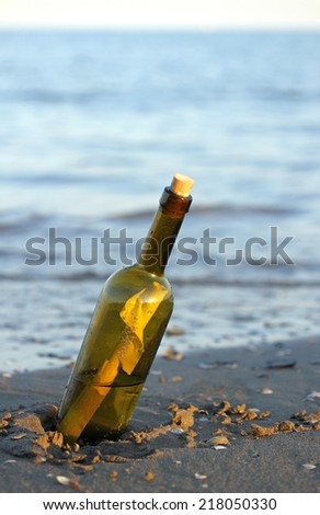 glass bottle with a secret message on the shore of sandy beach