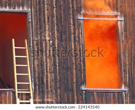 Dense orange smoke comes out of the window and a ladder of the fire near