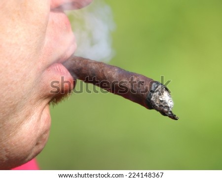 young smoker with long Cuban cigar in his mouth while smokes