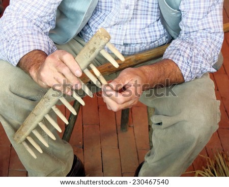 expert craftsman of wood while repairs an old wooden rake