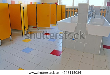 inside the bathroom of the nursery school with white ceramic sinks and doors yellow