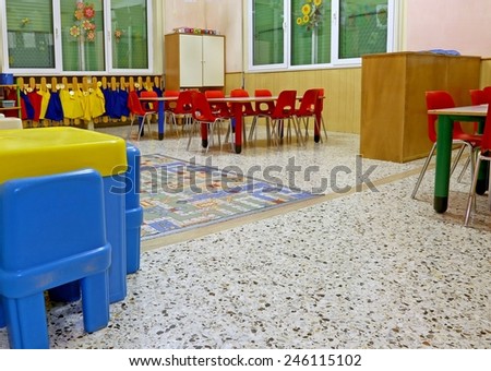 interiors of a nursery class with coloredchairs and  drawings of children hanging on the walls