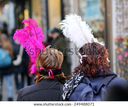 two masked women with big feathers around Venice during the Carnival