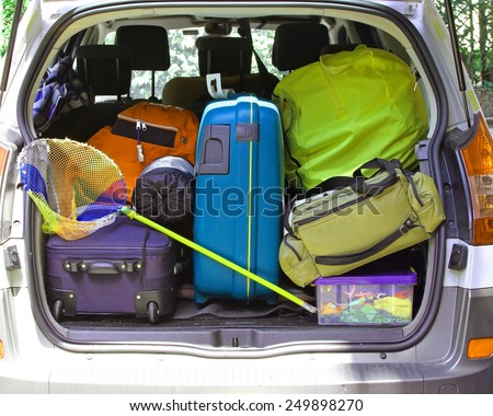 the trunk of the car with fishing net and luggage bags ready for the summer holidays
