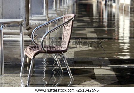single chair at high tide under the arcades during the flood in Venice  in italy