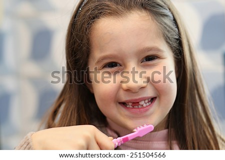 pretty little girl while washes the white teeth with a brush in bathroom