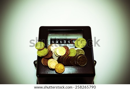 obsolete counter of electrical energy consumption with the number thirteen in display and european coins