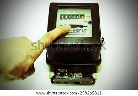 hand and a very old meter of electrical energy consumption with the number thirteen in display