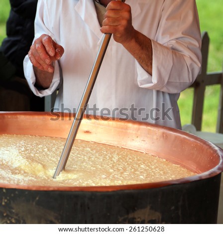 Elder cheesemaker boiling milk into the mixing pot for making cheese