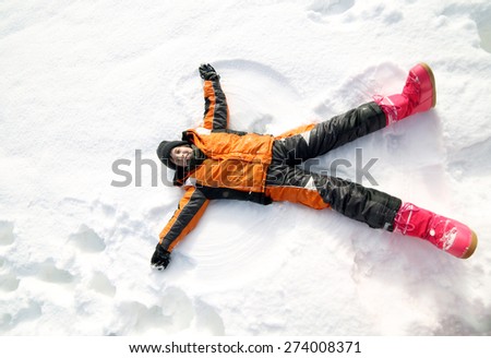 young boy creates the outline of an Angel in the snow in the mountains
