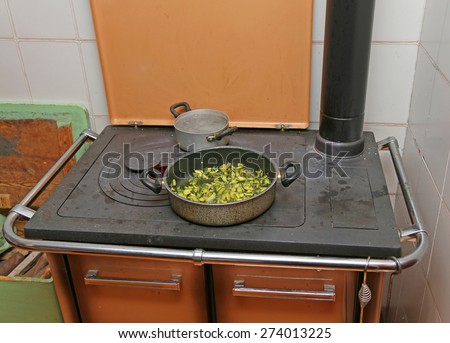 pan with zucchini baked in cast iron stove with fire lit in the old mountain home