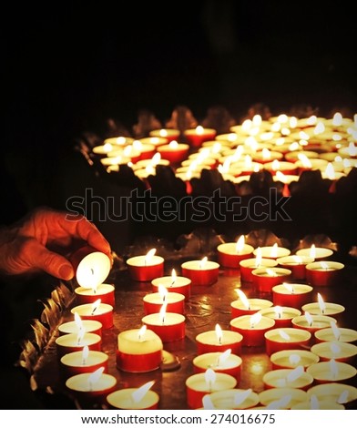 hand of an elderly woman lights a candle to pray during mass at Church