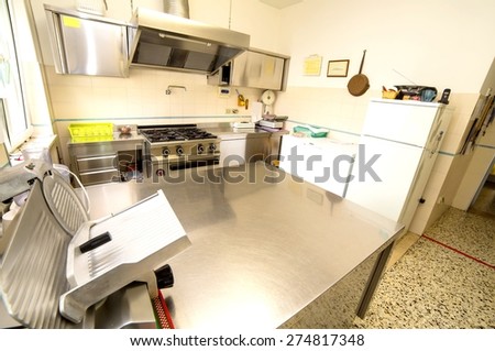 huge stainless steel kitchen with gas stove and a meat slicer