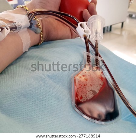 man\'s arm during the blood transfusion at the hospital with the needle in the arm